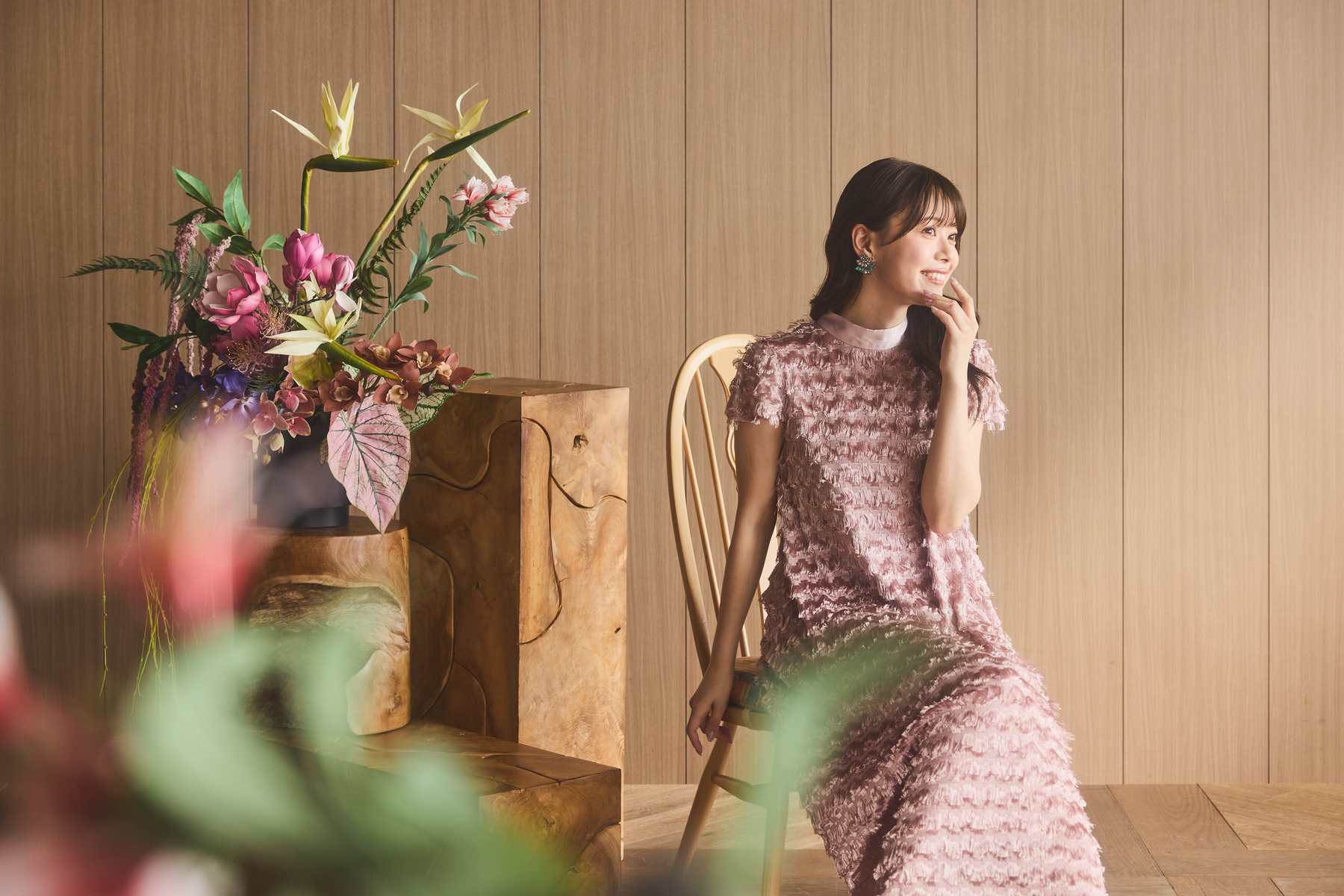 花を飾った空間でピンクのドレスを着た女性