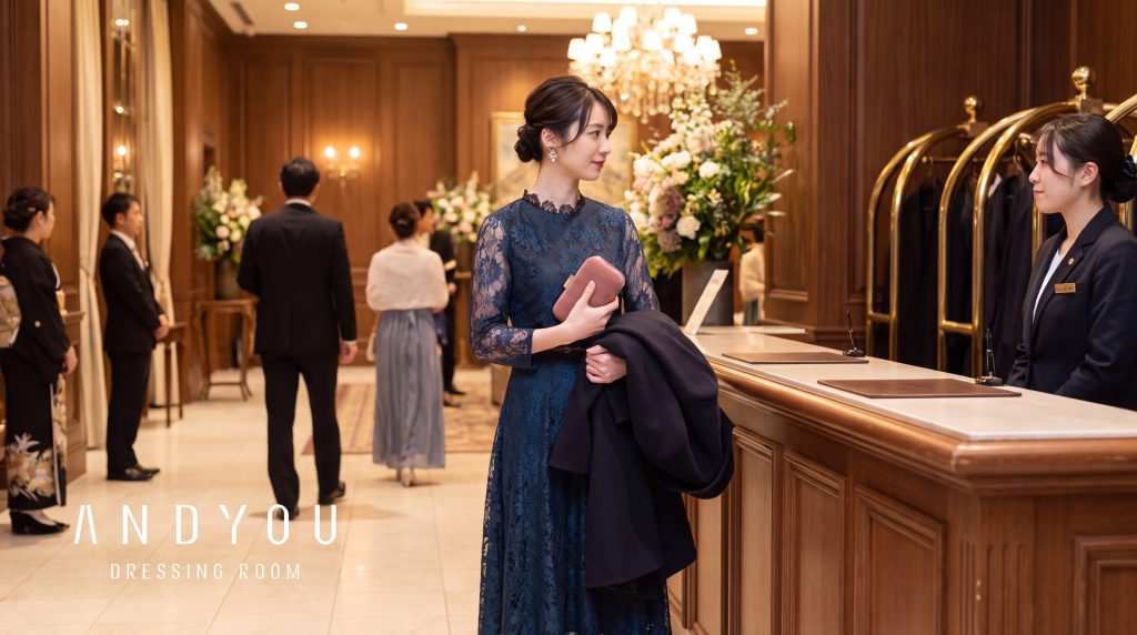 冬の結婚式会場のクロークでコートを預ける、ネイビーのレースドレスの女性