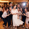 結婚式二次会で友人に囲まれて笑う、白いドレスの花嫁