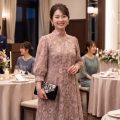 披露宴会場で微笑む、ハイネックのレースドレスを着た女性ゲスト