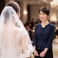 結婚式で花嫁を見つめる、ネイビーのフォーマルスーツを着た母親