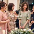 結婚式の披露宴会場で談笑する、パーティドレス姿の友人ゲスト4人